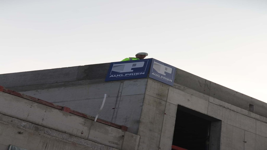 Der Polier steht bei seinem Richtspruch auf dem Flachdach des Betthaus Neubaus