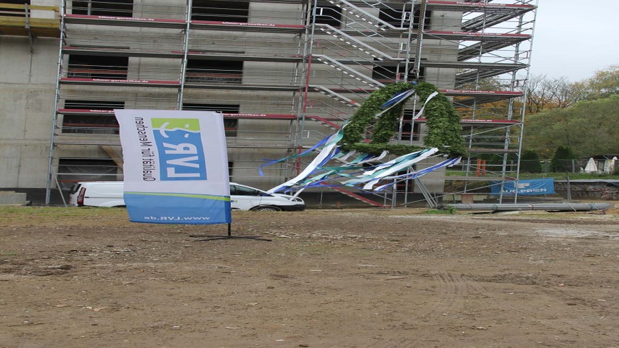 Richtkranz hängt am Kran. Links davon eine LVR-Flagge, im Hintergrund ein Teil des Neubaus