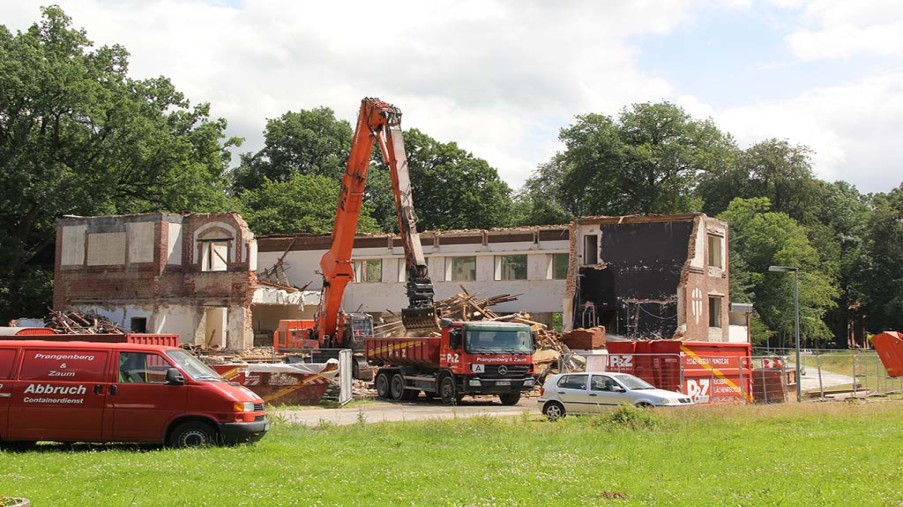 Das Dach und die halbe Front send entfernt, der Bagger beläd einen LKW mit Schutt.