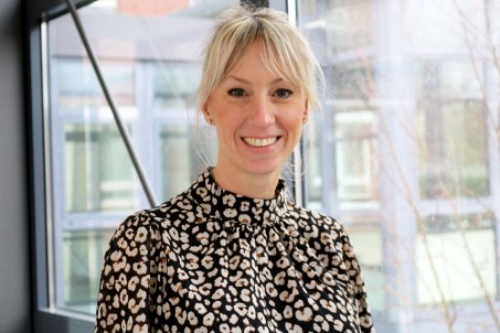 Junge Frau mit blonden Haaren sieht lächelnd in die Kamera