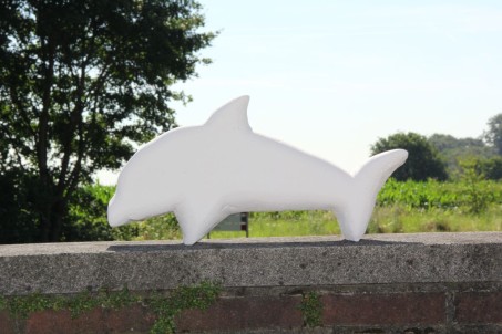 Delphin auf einer Mauer im Hinterdrund eine wiese mit Bäumen und Sträuchern - Skulptur aus der Gestaltungstherapie